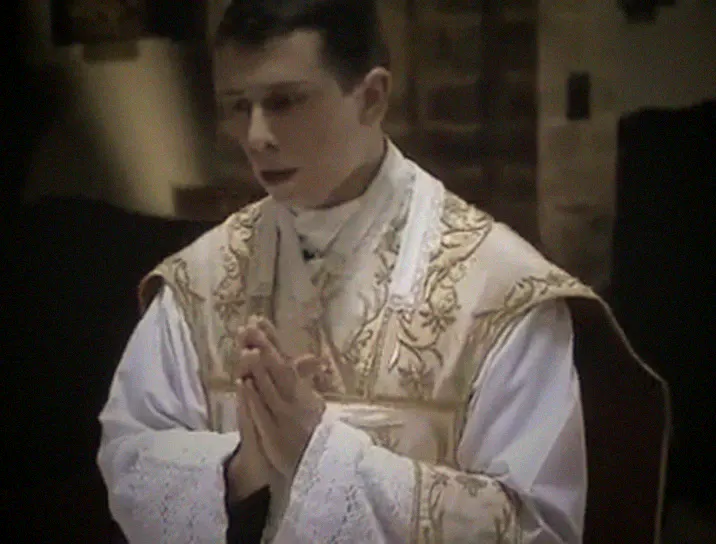 The priest at the centre of the altar, hands joined.