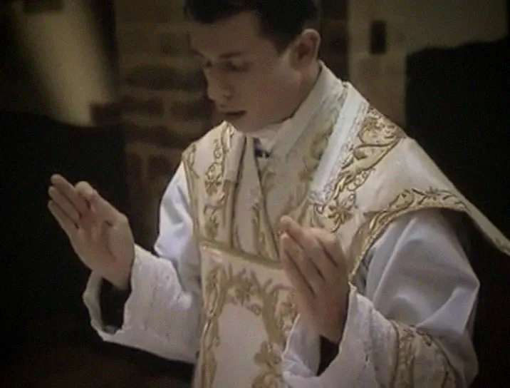 The priest prays the Our Father with his hands extended.