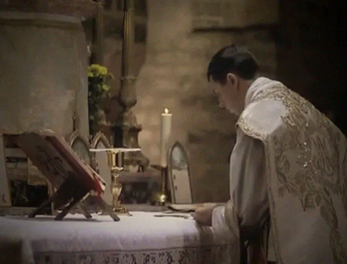 The priest bows over the altar in silent prayer before his Communion.